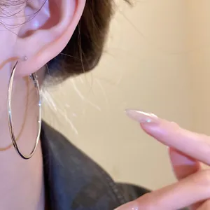 Close-up detail of minimalist large silver hoop earring worn on model's ear for style