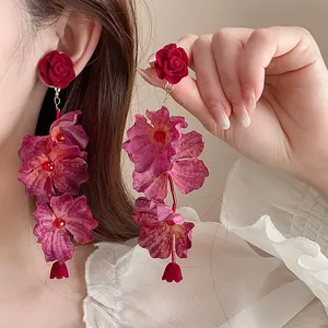 Close-up detail of burgundy velvet rose tiered flower drop earrings shown on model's ear