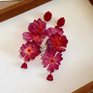 Detailed close-up of elegant handmade fabric flower drop earrings with red rose studs.