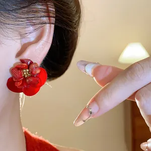 Elegant macro detail of retro red shell flower stud earrings worn by a model.
