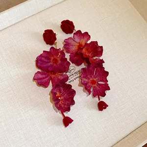 Close-up of elegant oversized red fabric floral drop earrings with vintage rose studs.