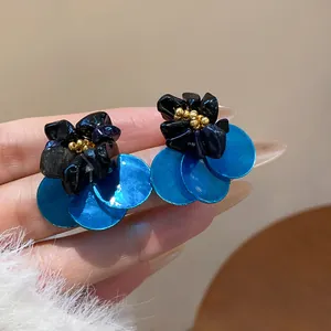 Detail view of vintage ethnic style earrings featuring blue sequins and dark floral stones.
