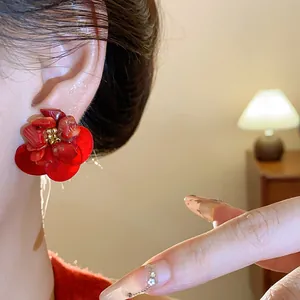 Detail of vintage red shell flower earrings with elegant gold-tone center on model's ear
