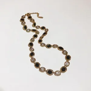 Elegant gold-tone clavicle necklace with alternating black and clear oval crystals