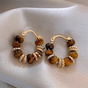 Detailed macro view of gold-plated hoop earrings with natural tiger eye stone beads.