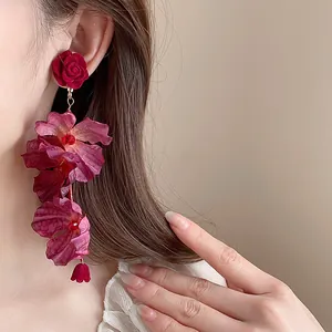 Macro shot of elegant long fabric rose flower petal drop earrings worn by a model