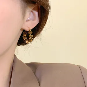 Close-up detail of retro gold-plated hoop earrings featuring natural tiger eye stone beads