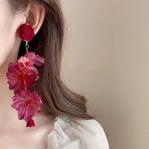 Detailed close-up of elegant long floral dangle earrings with dark red fabric roses