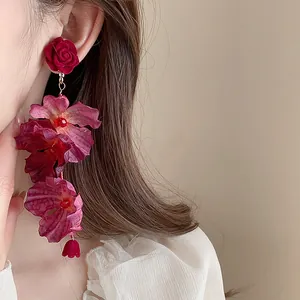 Detail view of exquisite red rose floral drop earrings with silk texture petals.