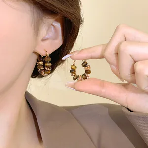 Close-up of vintage gold-plated hoop earrings featuring natural tiger eye beads
