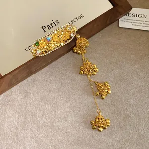 Detailed view of ethnic style golden hair clip with rhinestone flower and bell tassels