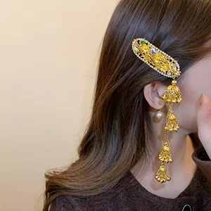 Detail of an ethnic style gold hair clip with rhinestones and multi-layer bell tassels