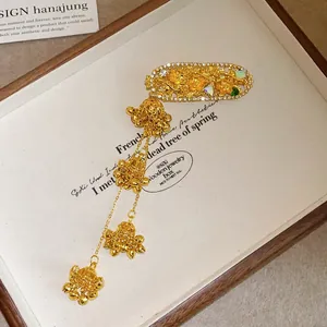 Detailed view of golden floral rhinestone hair clip with dangling bell tassels
