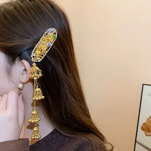 Detailed side view of a vintage gold hair clip with rhinestones and bell tassels