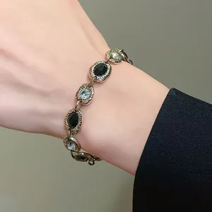 Detailed view of a vintage gold-tone bracelet with black and clear crystal inlays on a wrist.