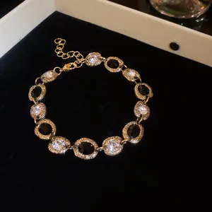 Detailed macro view of a gold oval link necklace featuring black and clear crystal accents