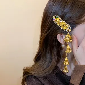 Detailed side view of vintage gold floral hair clip with dangling bell tassels on hair