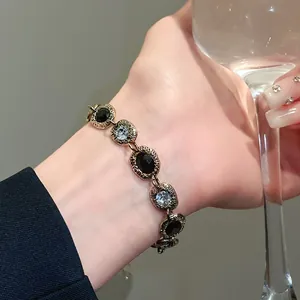 Detail of vintage gold-tone bracelet with black gems and sparkling crystals on wrist.