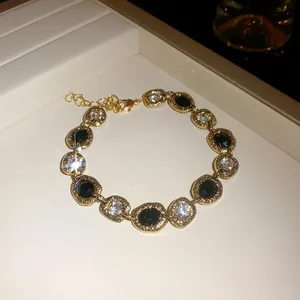 Elegant gold necklace with black and clear crystals set in irregular oval frames