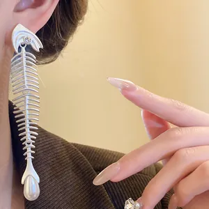 Detailaufnahme kreativer Fischgräten-Ohrring in Silber mit Perle und Schmuckstein