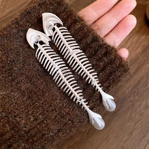 Detailansicht der silbernen Fischgräten-Ohrringe mit Kristallaugen und Perlen.