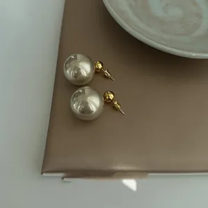 Close-up detail of French style gold-plated silver needle pearl earrings for women