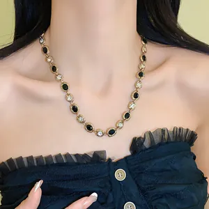 Detail of elegant gold-tone oval necklace with black stones and crystals on neck.