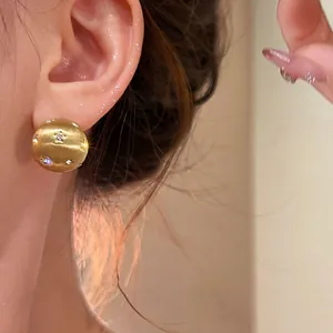 Close-up of vintage 18K gold plated brushed stud earrings with sparkling zircons