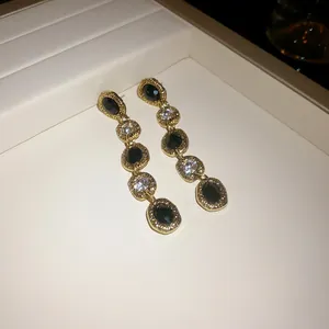 Detailed view of elegant gold drop earrings featuring black and clear irregular oval stones