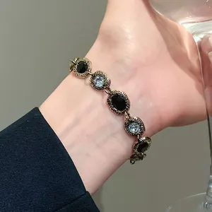 Close-up of vintage gold bracelet with black and clear stones worn on a female wrist