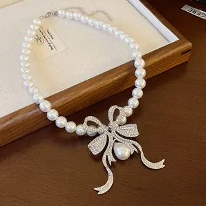 Detail view of an elegant pearl necklace featuring a sparkling rhinestone bow pendant.