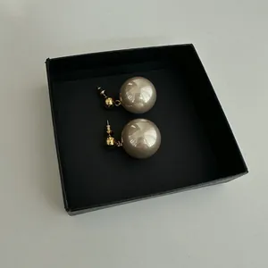 Detailed view of French style champagne pearl earrings in a black gift box