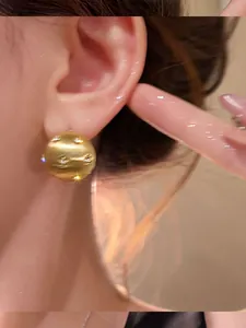 Detailed close-up of 18K gold-plated brushed oval earrings with sparkly zircon accents.