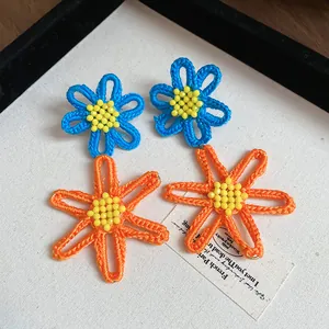 Handmade crochet flower earrings in vibrant blue and orange with yellow bead centers
