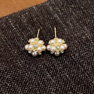 Elegant pearl cluster stud earrings with shining crystals on dark brown textured fabric