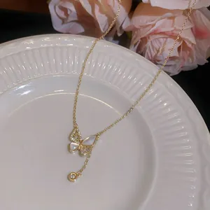 Detailopname van een vergulde vlinderketting met zirkonen en parelmoeren vleugels