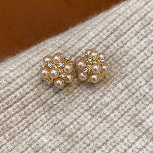 Elegant pearl flower cluster stud earrings with rhinestones on beige knit background