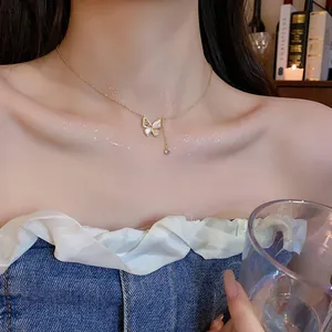 Close-up van een elegante gouden vlinderketting met schelpenvleugels gedragen door een model
