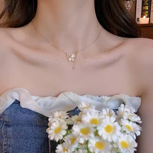 Elegante gouden vlinderketting met zirkonia en details van schelpinleg op de nek