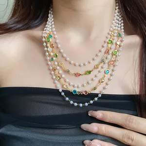 Dettaglio di una collana multistrato con perle bianche e cristalli colorati su una modella.