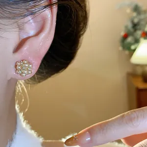 Close-up of elegant pearl cluster stud earrings with small diamond accents on woman's ear.