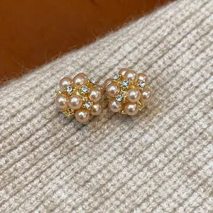 Detailed macro view of elegant champagne pearl flower cluster stud earrings on knit