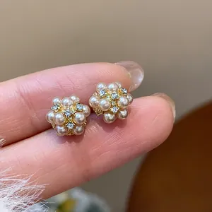 Macro view of cluster pearl stud earrings with rhinestone accents on a gold-tone base
