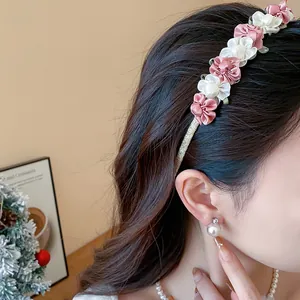 Detailaufnahme eines eleganten Haarreifens mit rosa und weißen Stoffblumen am Modell