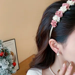 Nahaufnahme eines eleganten Stoff-Blumen-Haarreifs, getragen mit Perlenohrringen