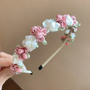 Nahaufnahme eines Stirnbandes mit zarten rosa und weißen handgefertigten Stoffblumen