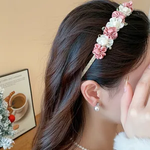Detailansicht eines süßen Stoffblumen-Haarreifs mit rosa und weißen Blüten am Modell