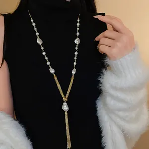 Macro view of an elegant gold-toned sweater necklace with faux pearls and long tassels