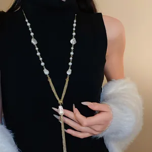 Detailed view of elegant gold tassel necklace with white pearls on black sweater.