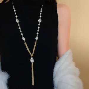 Macro detail of vintage pearl tassel necklace showing delicate gold chains and lustrous pearls.